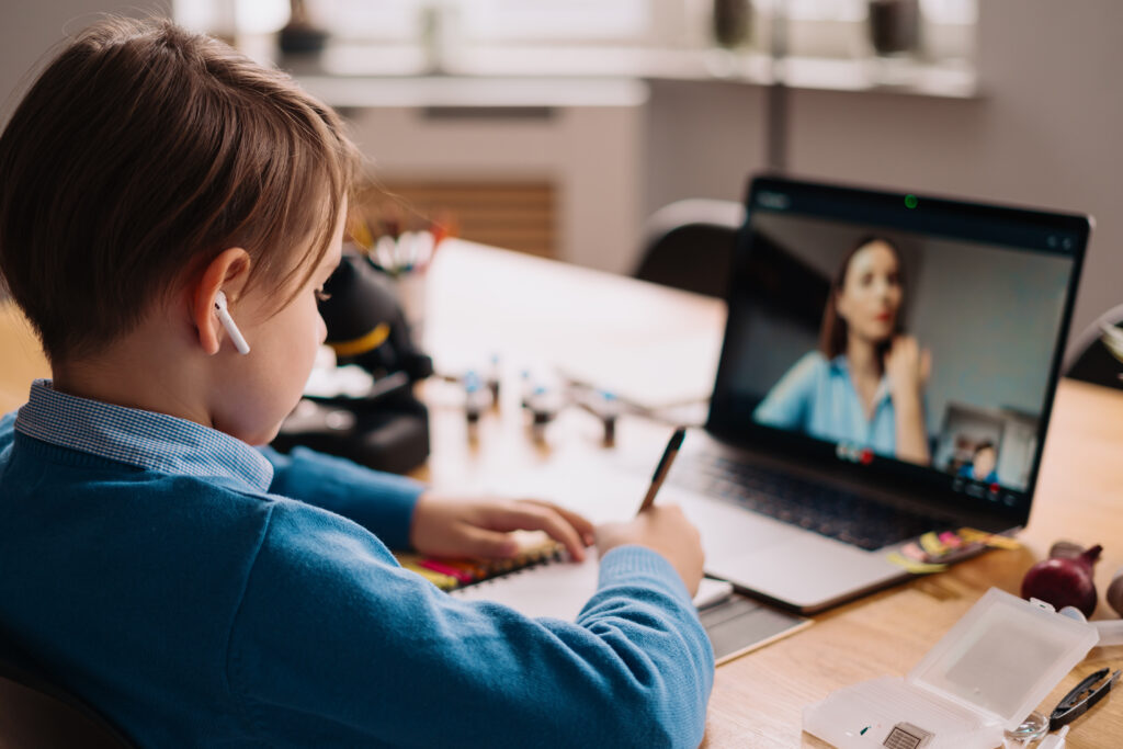 A Preteen boy uses a laptop to make a video call with his tutor