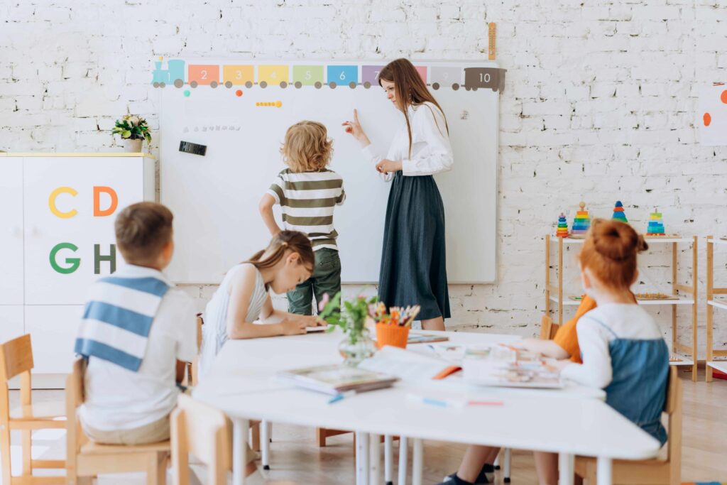 Teacher with her pupil standing near the whiteboard